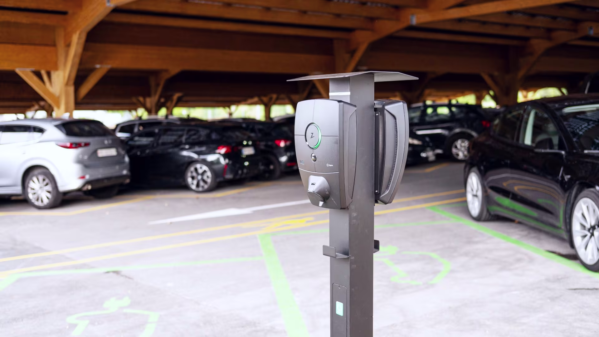 Zaptec Pro Ladestation für Elektrofahrzeuge in einem überdachten Firmenparkplatz mit mehreren ladenden Fahrzeugen