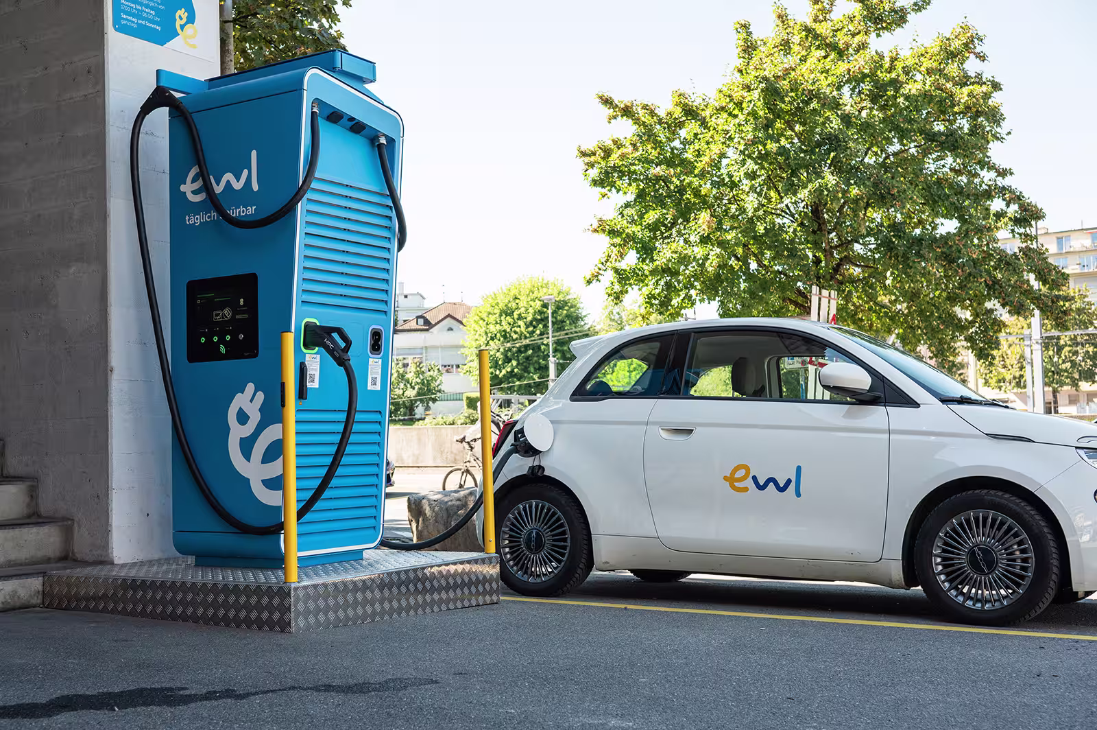 Weisses Elektroauto von ewl lädt an einer blauen DC-Schnellladestation von ewl