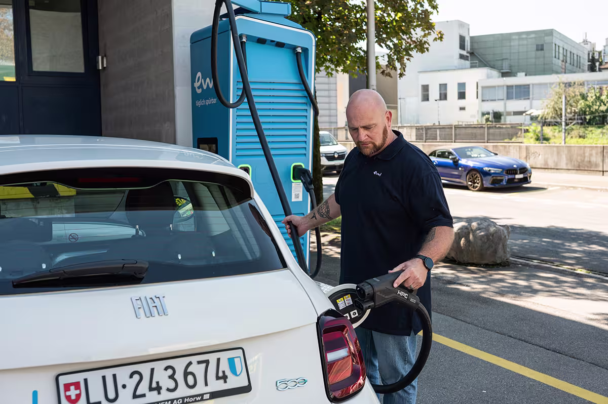 Mitarbeiter steckt einen HPC-Ladestecker der ewl-DC-Ladestation in ein Elektroauto